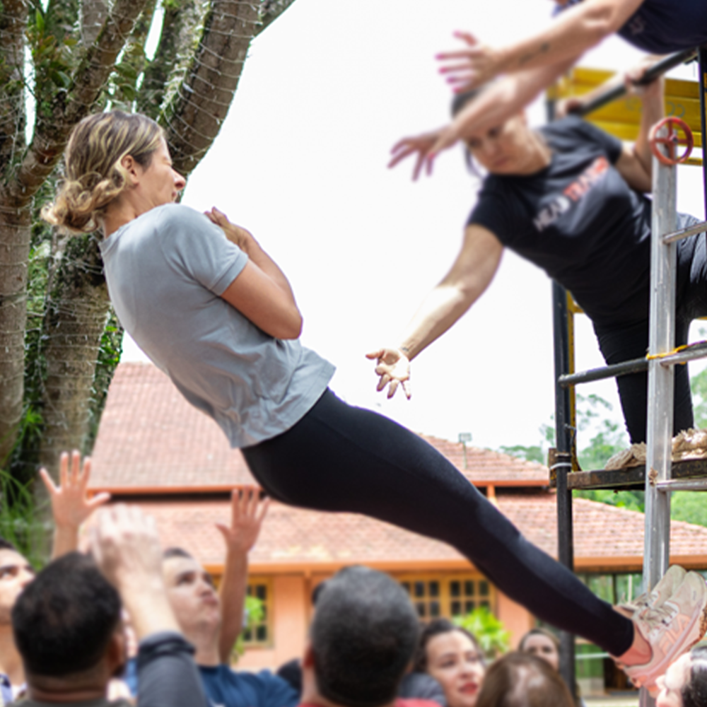 Alex dando um salto de fé para ser segurada pelas pessoas no cháo.